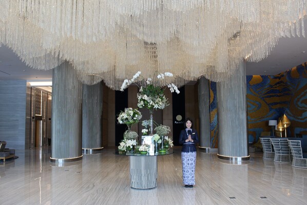 Un vestíbulo con un arreglo floral central sobre una mesa de vidrio, rodeado de asientos.