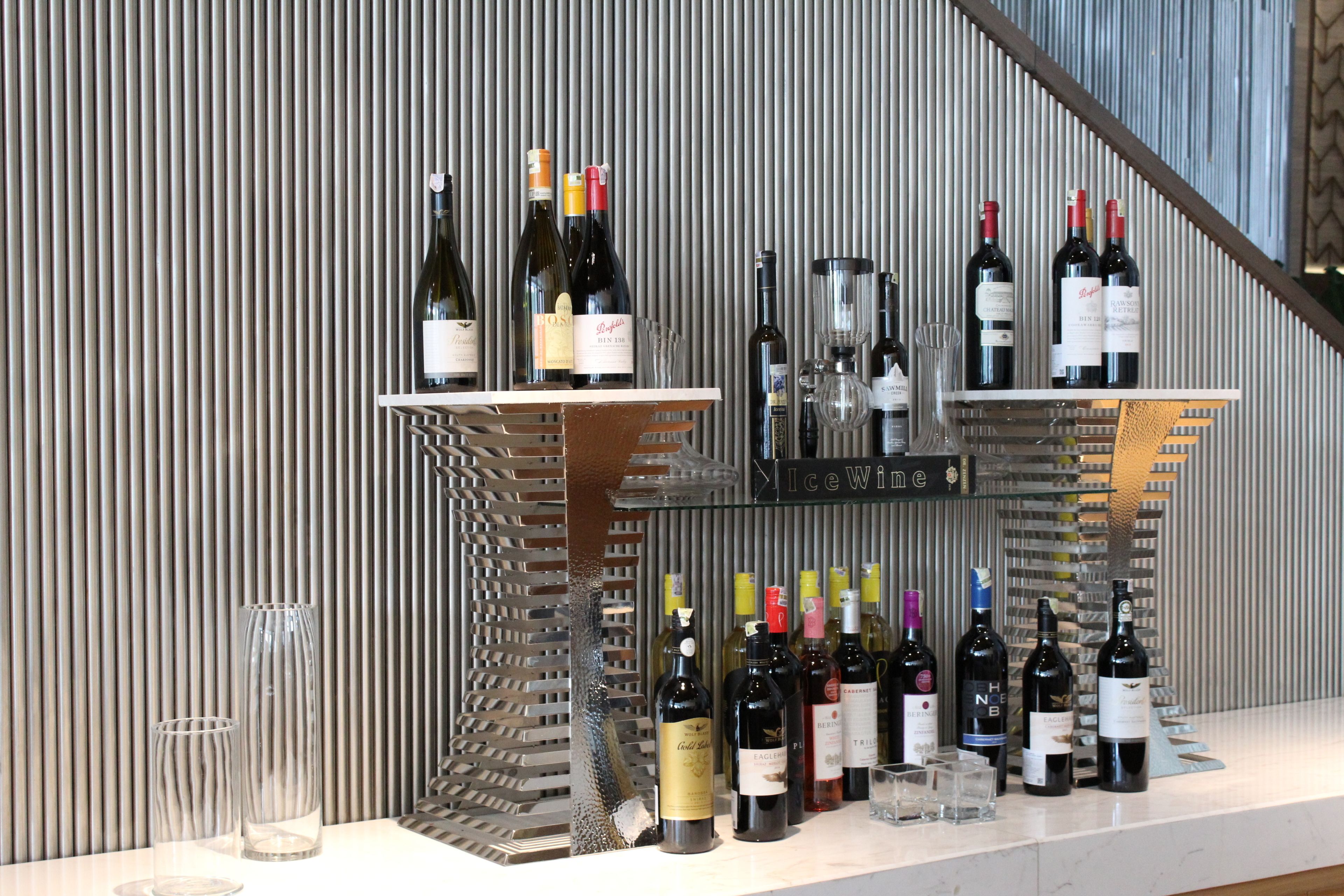 A wine display with various bottles and glasses against a textured wall.