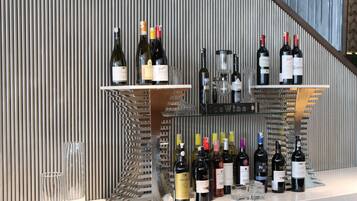 A wine display with various bottles and glasses against a textured wall.