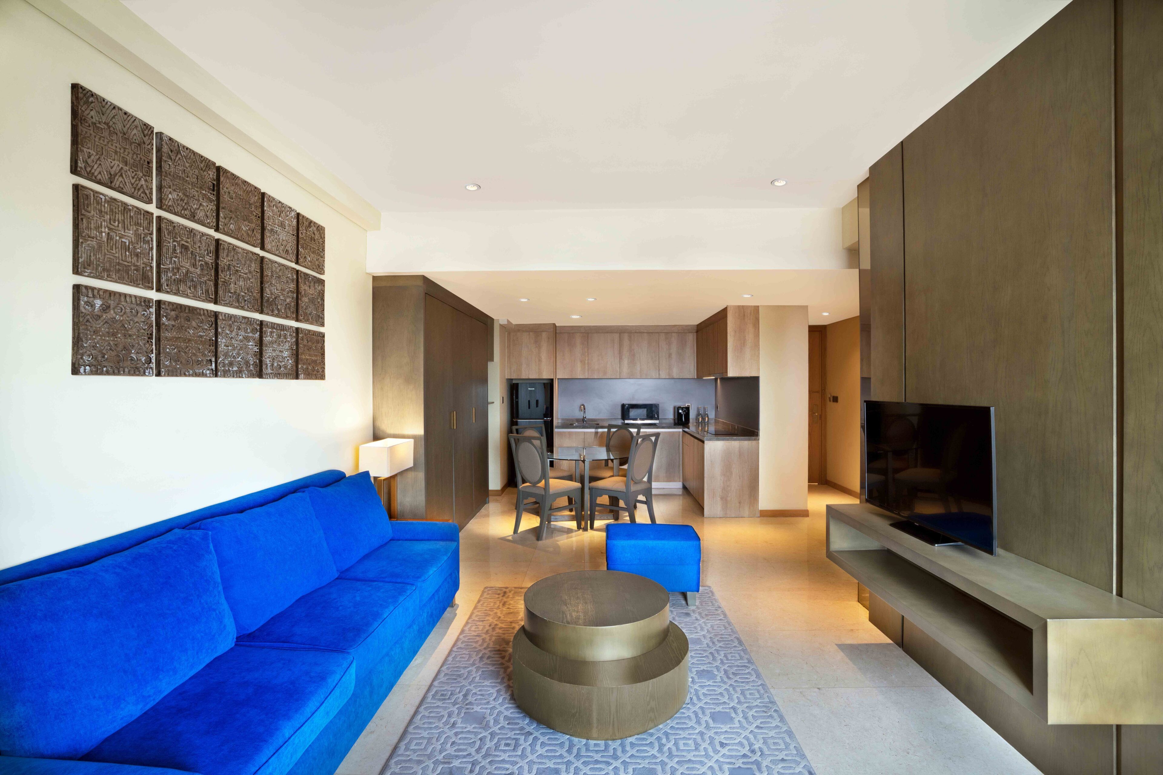 A modern living room with a blue sofa, a coffee table, and a TV mounted on a wooden wall.