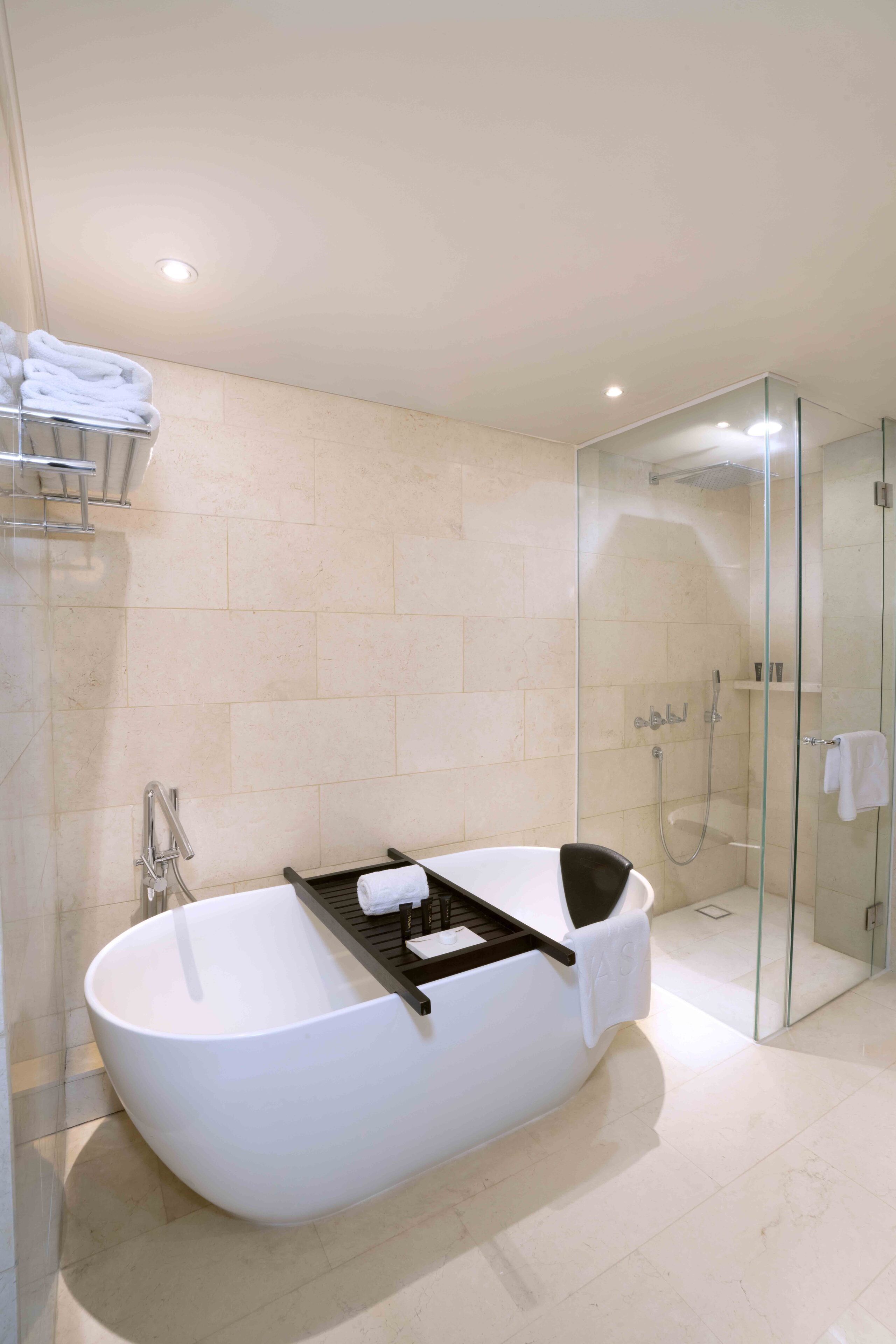 A modern bathroom with a freestanding bathtub, glass shower enclosure, and a towel rack.