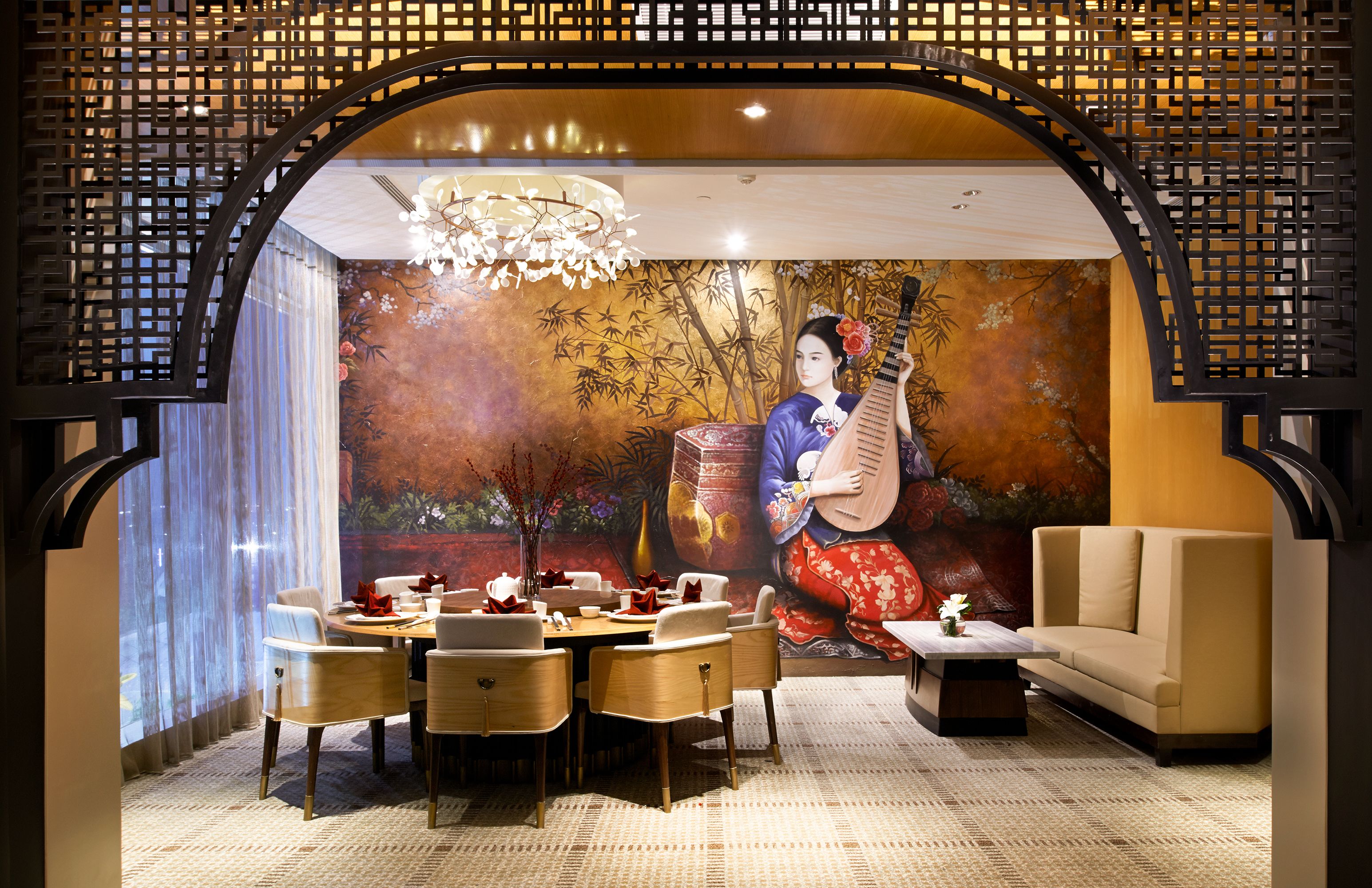 A traditional-style dining area with a mural, wooden furniture, and a modern sofa.