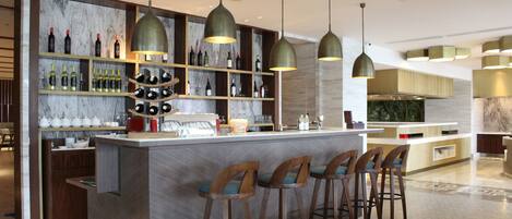 A modern bar area with a marble backsplash, wooden shelves with bottles, and pendant lighting.