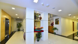 A modern hotel lobby with a polished floor, a reception desk, and potted plants. - Hotel H Valley Yangon (Yangon)