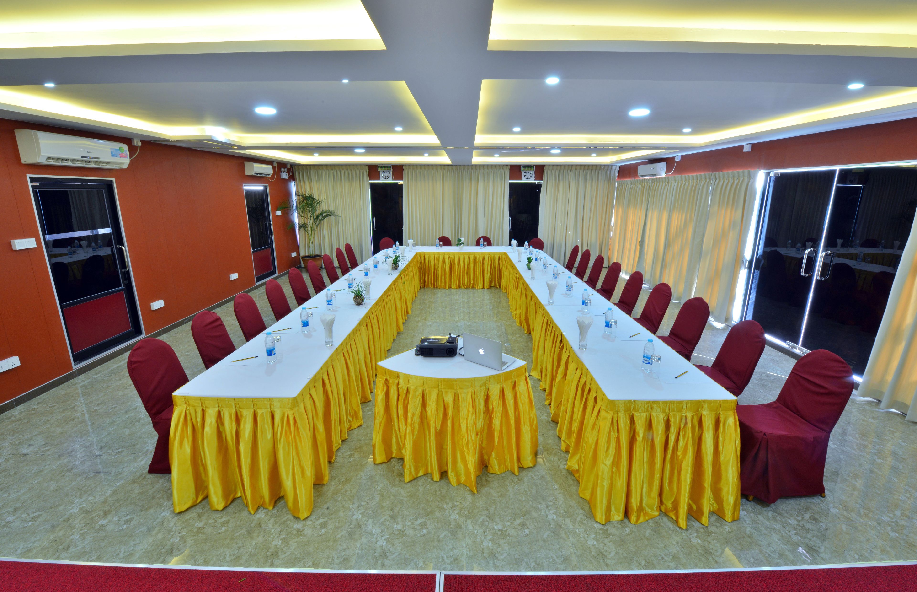A conference room with a long table, red chairs, and a laptop.