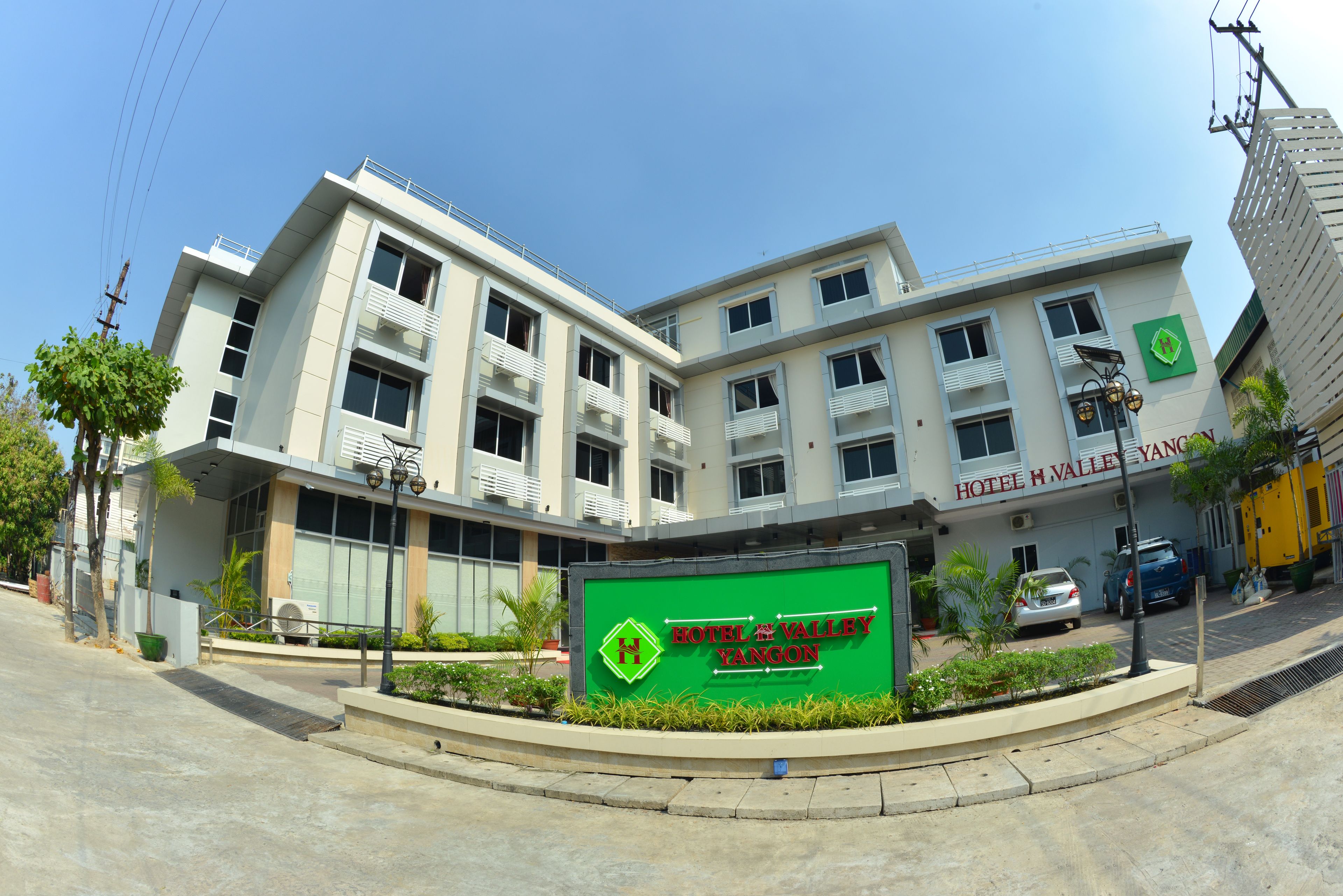 A multi-story hotel with a prominent sign for Hotel H Valley Yangon.