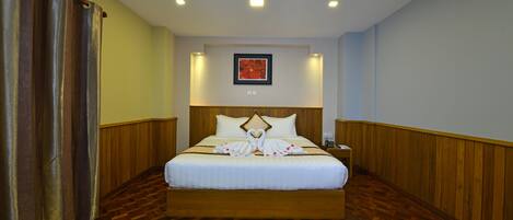 Habitación de hotel con una cama grande, paneles de madera, un cuadro en la pared y un par de pantuflas en el suelo.