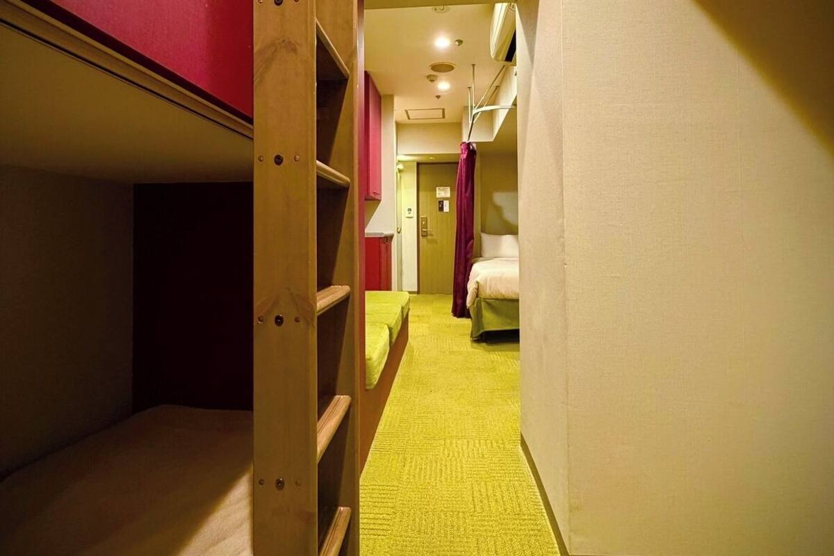 A narrow hallway with bunk beds on one side and a single bed on the other.