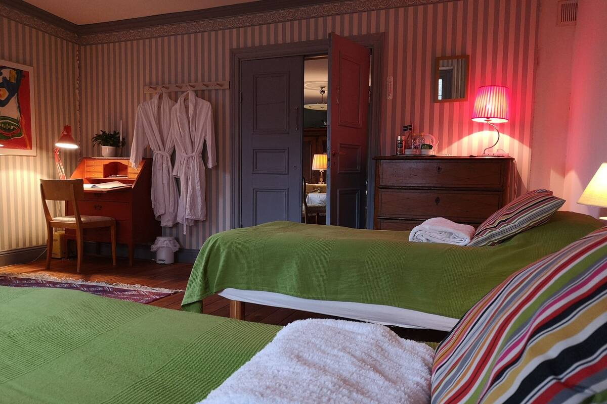 Ein Hotelzimmer mit einem grünen Bett, einem Holztisch, einem Stuhl und einem Kleiderschrank.