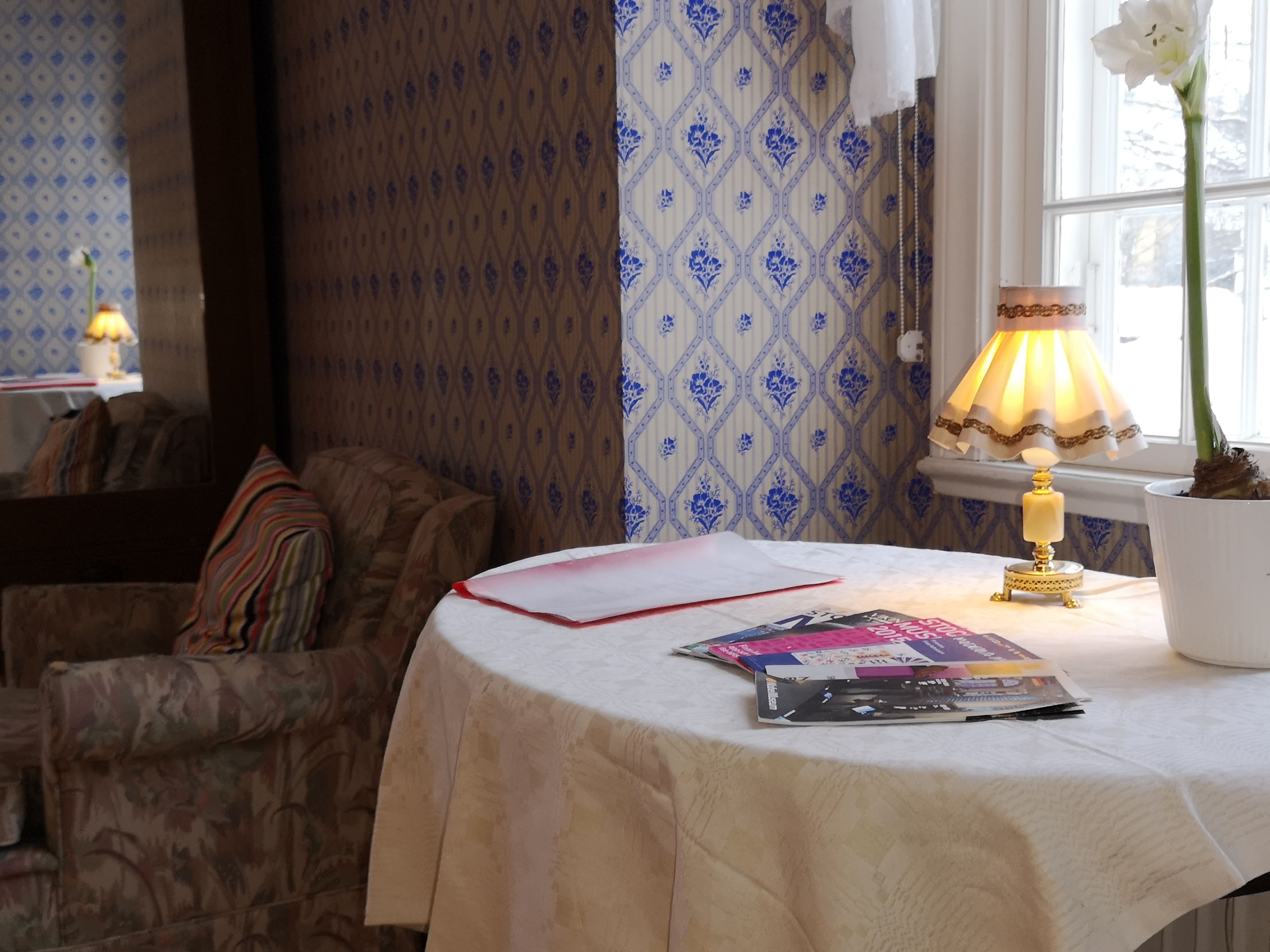 A cozy room with a round table, a lamp, and a potted plant.