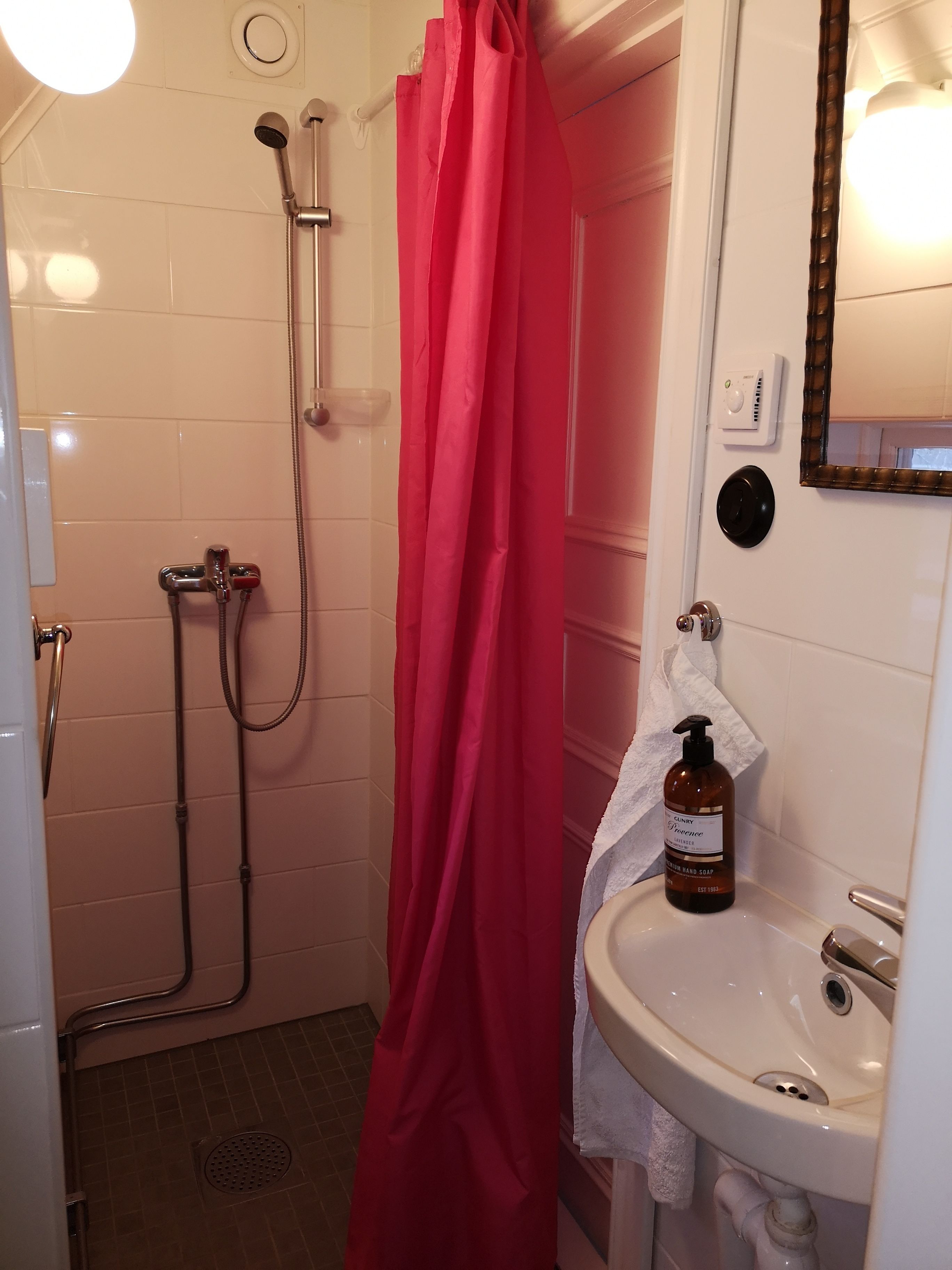 A bathroom with a shower, a sink, and a mirror.