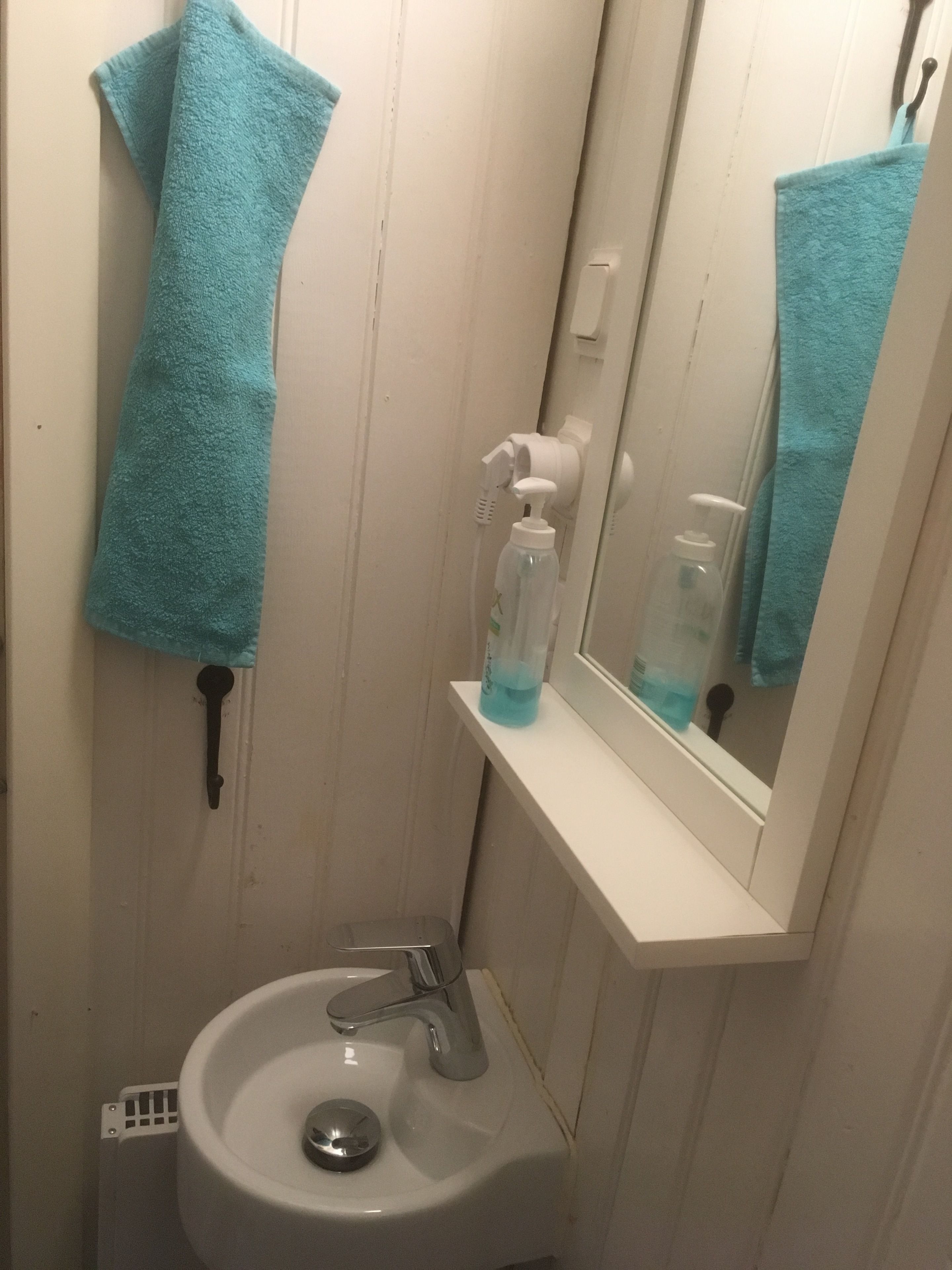 Un baño con un lavamanos blanco, un espejo y una toalla colgada en la pared.