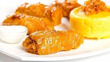 Un plato de rollos de col rellenos, acompañados de salsa y un cuenco pequeño de salsa blanca.