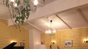 Een gezellige woonkamer met een vleugelpiano, een open haard, een comfortabele bank en een eethoek.
