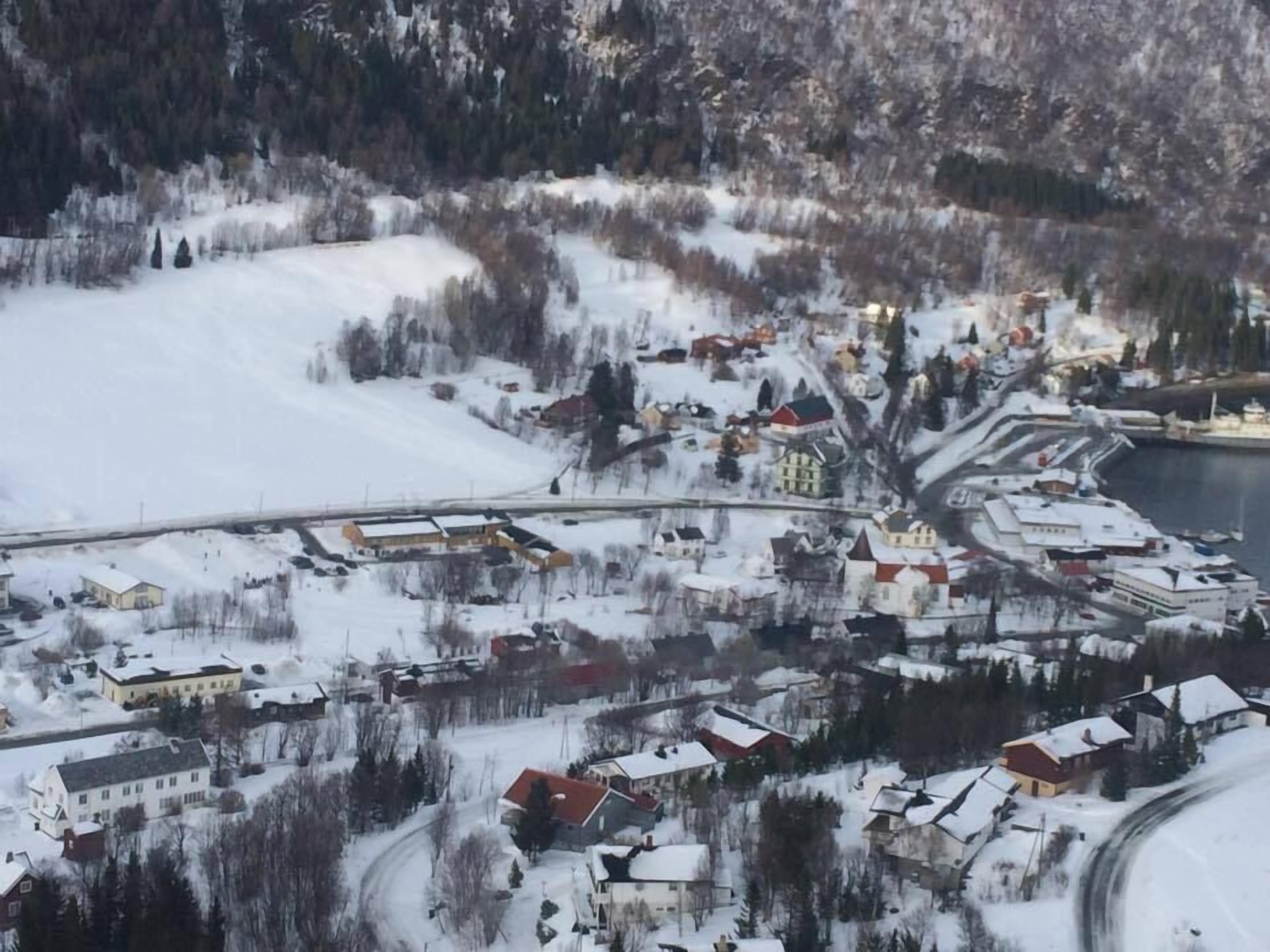 Lumipeitteinen kaupunki, jossa on rakennuksia, silta ja vesistö.
