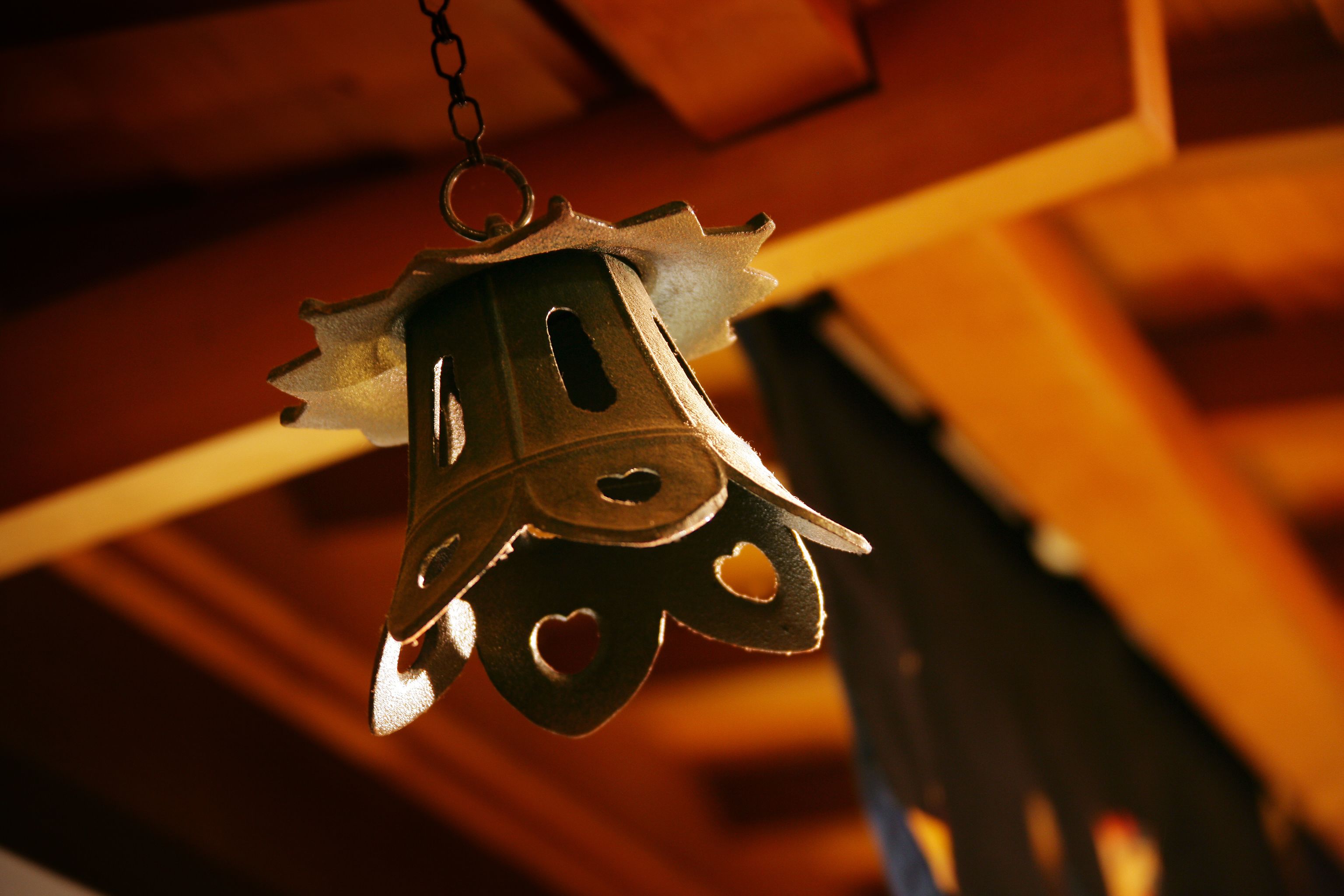 A hanging bell with heart-shaped cutouts.