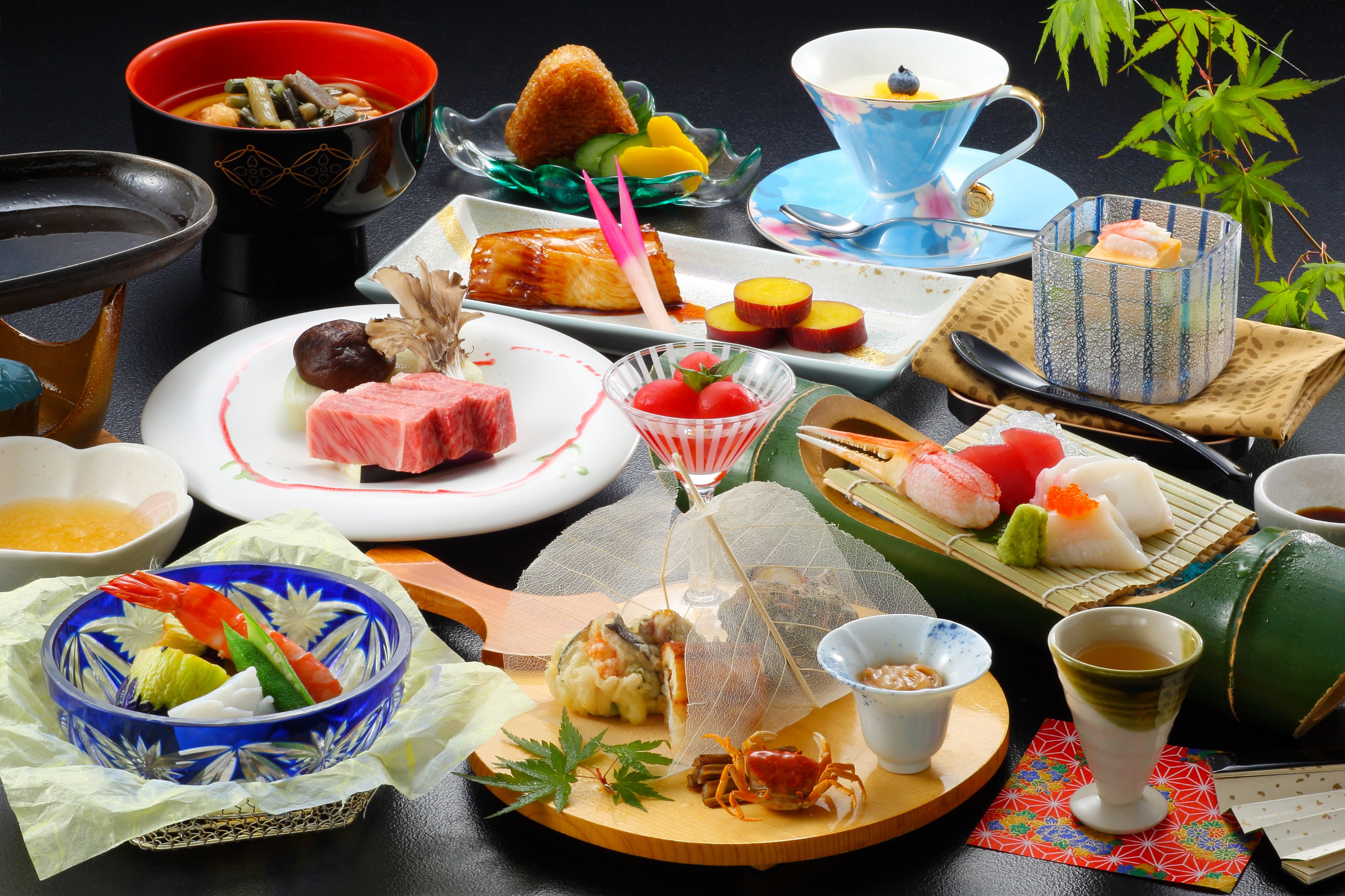 Forskellige japanske retter, herunder sushi, sashimi og tempura, serveret på traditionelt keramik og drikkeglas.
