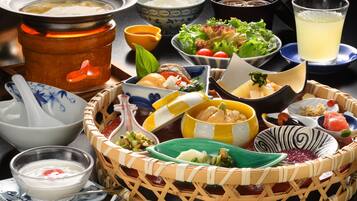 Una variedad de platos y tazones sobre una mesa, incluyendo un recipiente con comida caliente, arroz y diferentes acompañamientos.