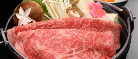 A hot pot with raw meat, mushrooms, and vegetables.