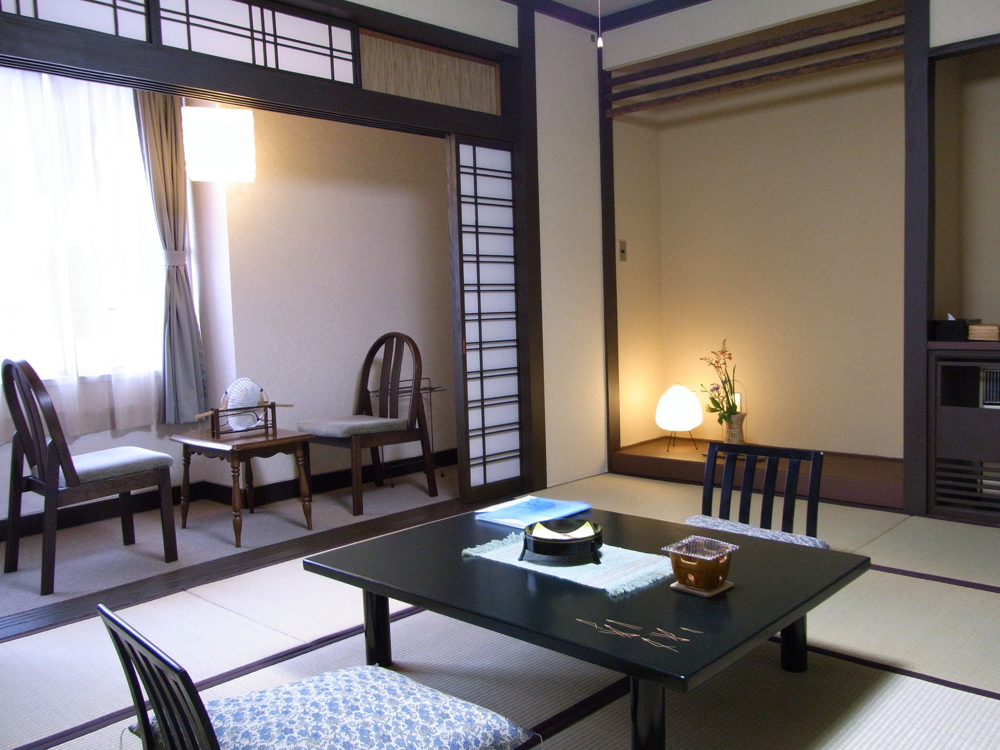 A traditional Japanese-style room with tatami flooring, a low table with a tea set, and a shoji screen.