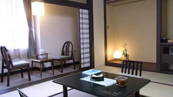 A traditional Japanese-style room with tatami flooring, a low table with a tea set, and a shoji screen.
