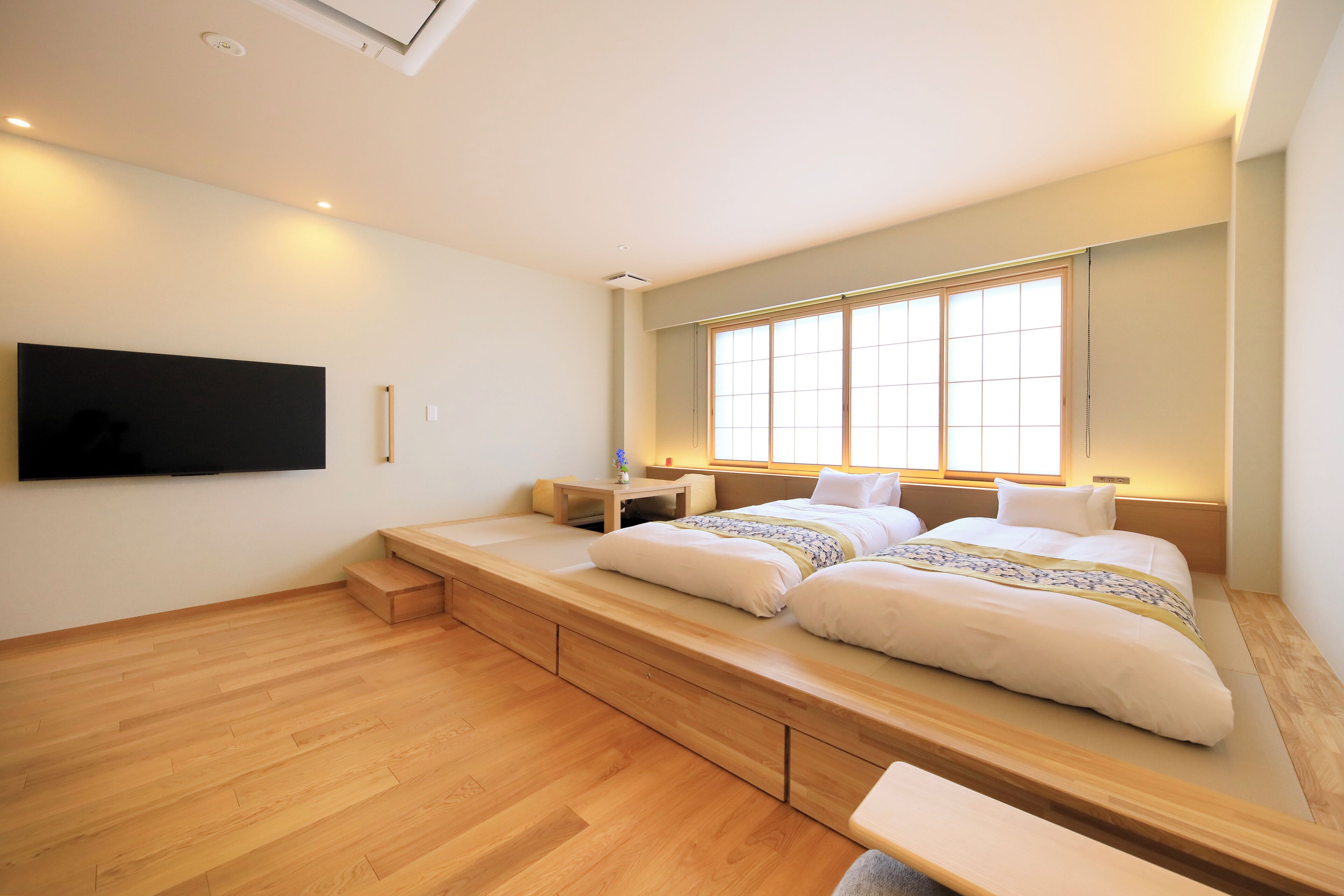 A bedroom with a large bed, built-in storage, a bedside table, and a TV mounted on the wall.