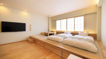 A bedroom with a large bed, built-in storage, a bedside table, and a TV mounted on the wall.