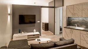 Un soggiorno moderno con TV a schermo piatto, una consolle bianca, un divano e un tavolino.