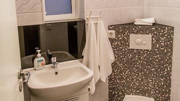 Une salle de bain équipée d’un lavabo, de toilettes et d’une fenêtre située au-dessus du lavabo.