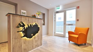 Una reception con un design nero originale e tagliato, un pavimento in legno e una sedia arancione in un’accogliente hall moderna.