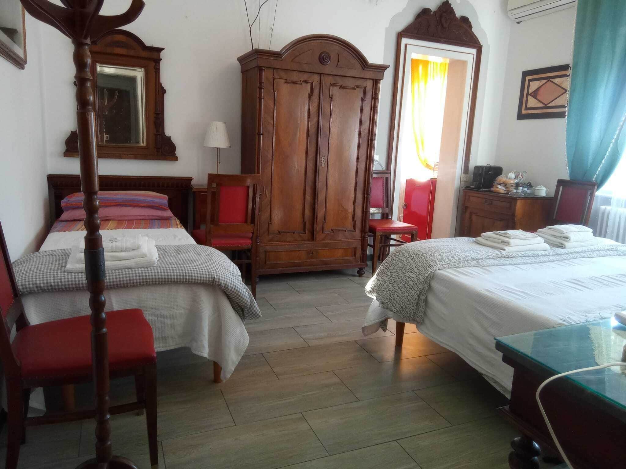 A hotel room with two beds, a wardrobe, a desk, and a chair.
