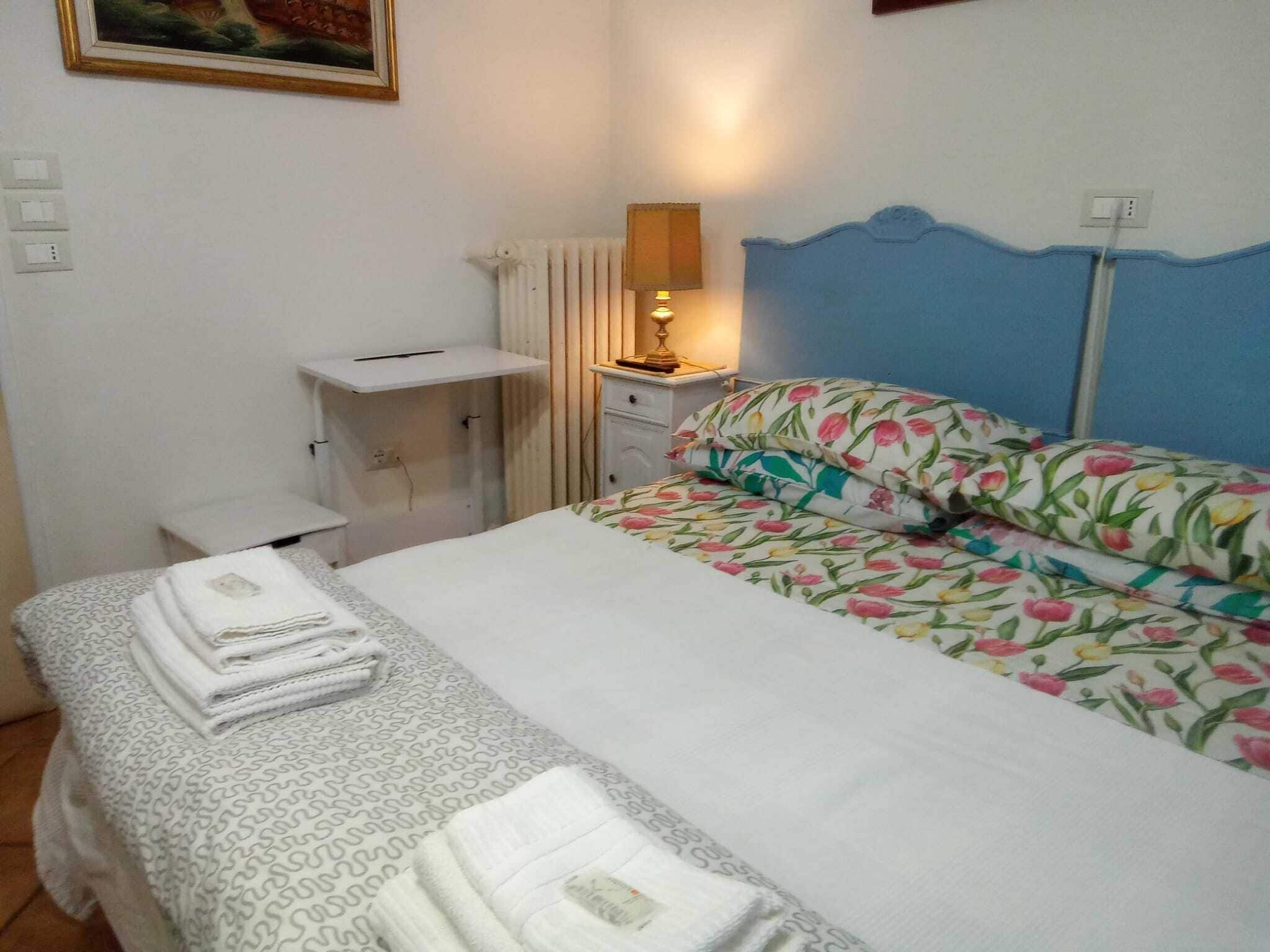A bedroom with a bed, a bedside table, a lamp, and a radiator.