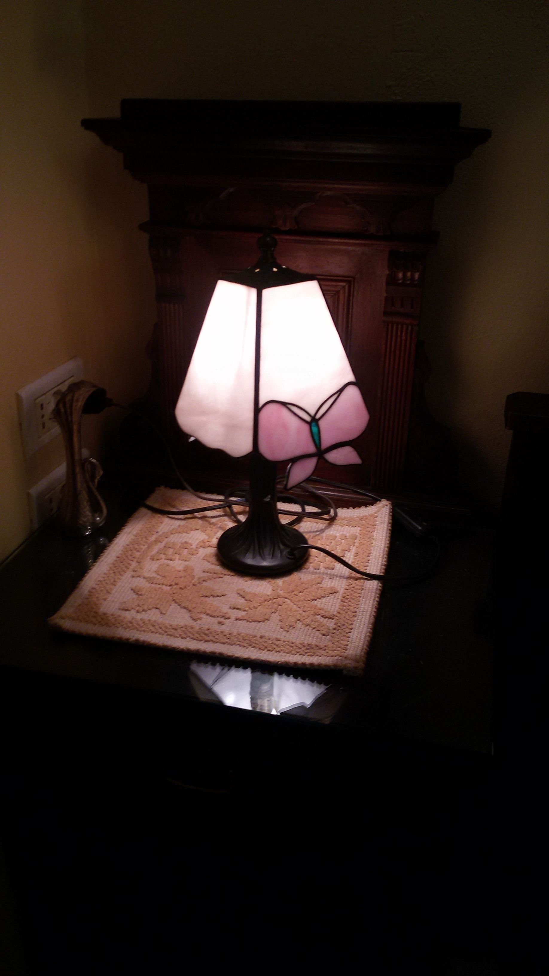 Una lámpara de mesa con pantalla floral sobre un mantel texturizado.