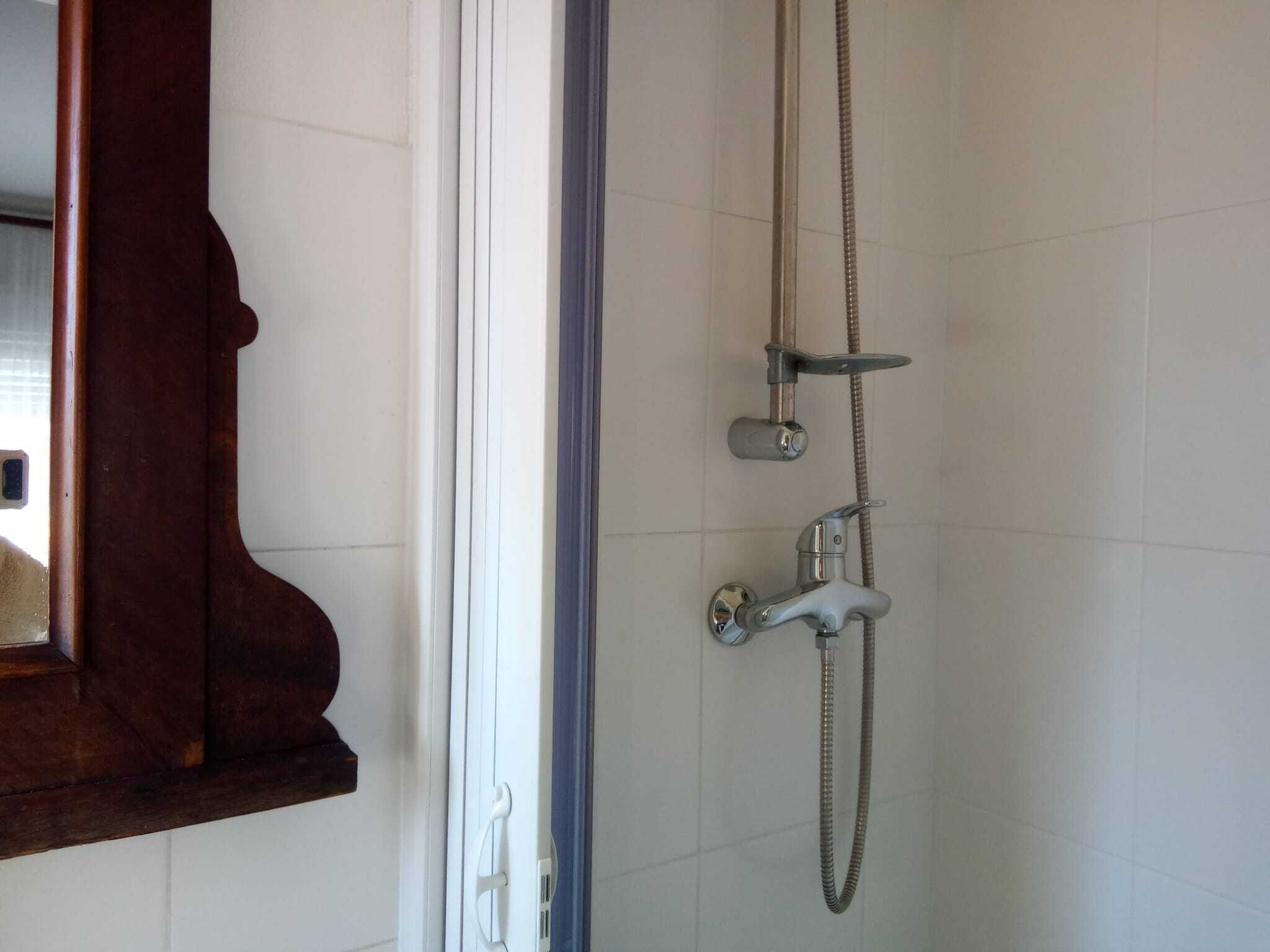 A shower with a handheld showerhead and a wall-mounted faucet.