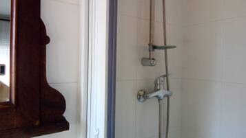 A shower with a handheld showerhead and a wall-mounted faucet.
