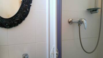 Une salle de bain avec une douche, un lavabo et un miroir décoratif.
