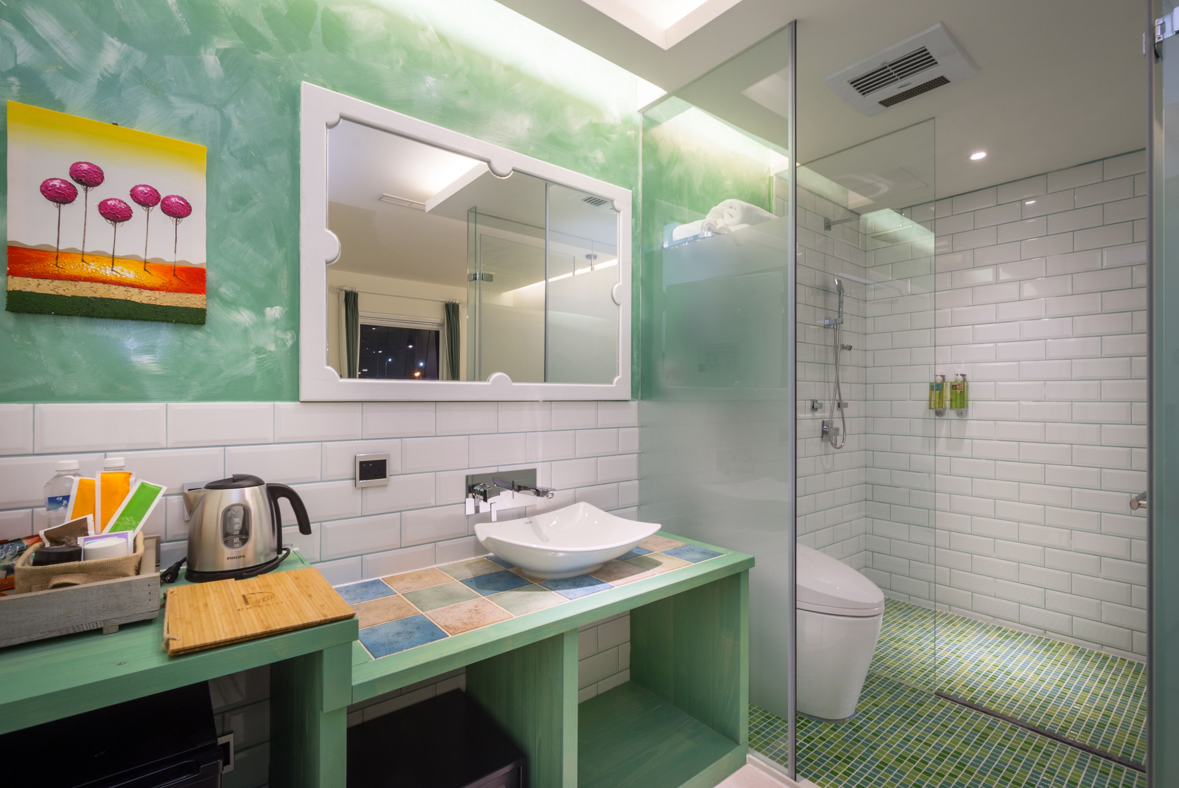 A bathroom with a green countertop, a white sink, and a glass-enclosed shower.