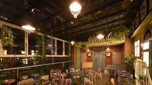 A cozy, well-lit indoor space with a variety of seating options, including tables and chairs, and is adorned with hanging plants and decorative lighting. - DG Hotel (Taipei)