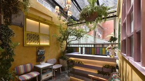 A cozy courtyard with a wooden bench, striped chairs, and hanging plants. - DG Hotel (Taipei)