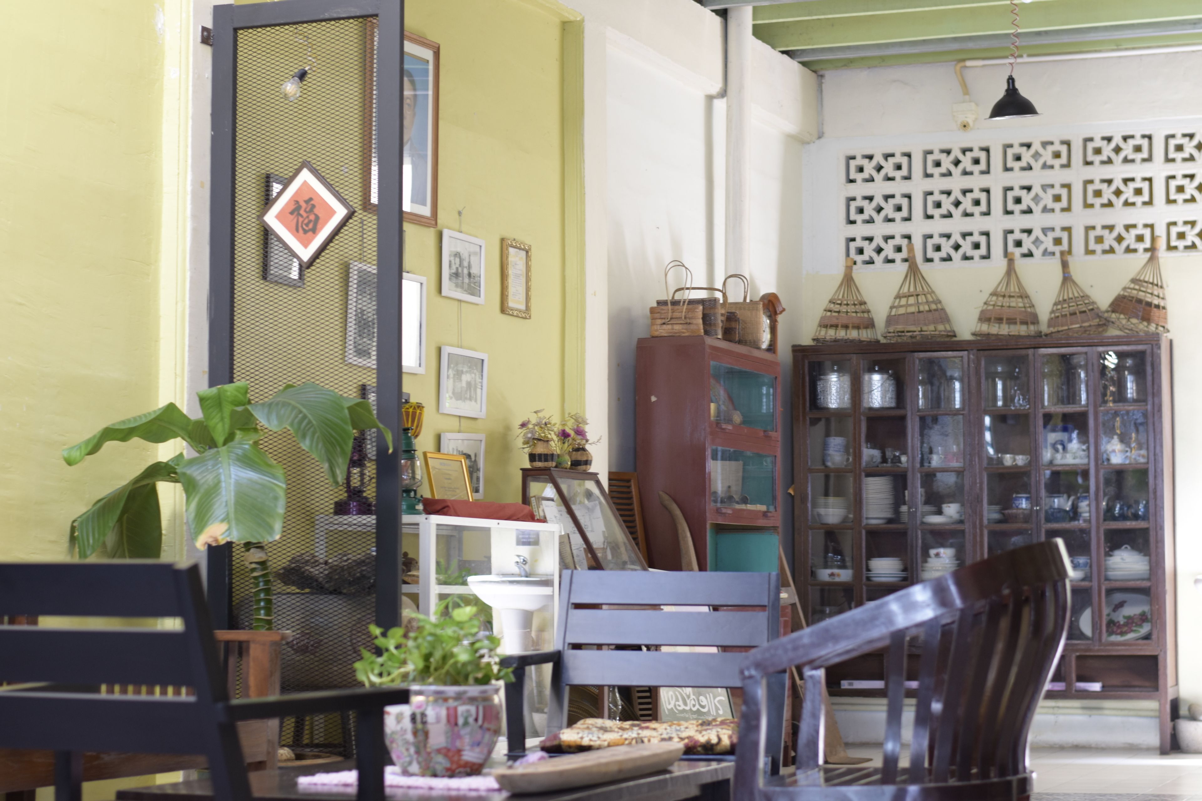 A room with a dining table, chairs, a potted plant, a cabinet with glass doors, and a wall with decorative patterns.