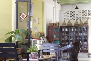 Een kamer met een eettafel, stoelen, een potplant, een kast met glazen deuren en een wand met decoratieve patronen.