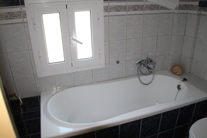 A bathroom with a bathtub, a window, and a toilet. - Dimitra's Maisonette (Corfu)
