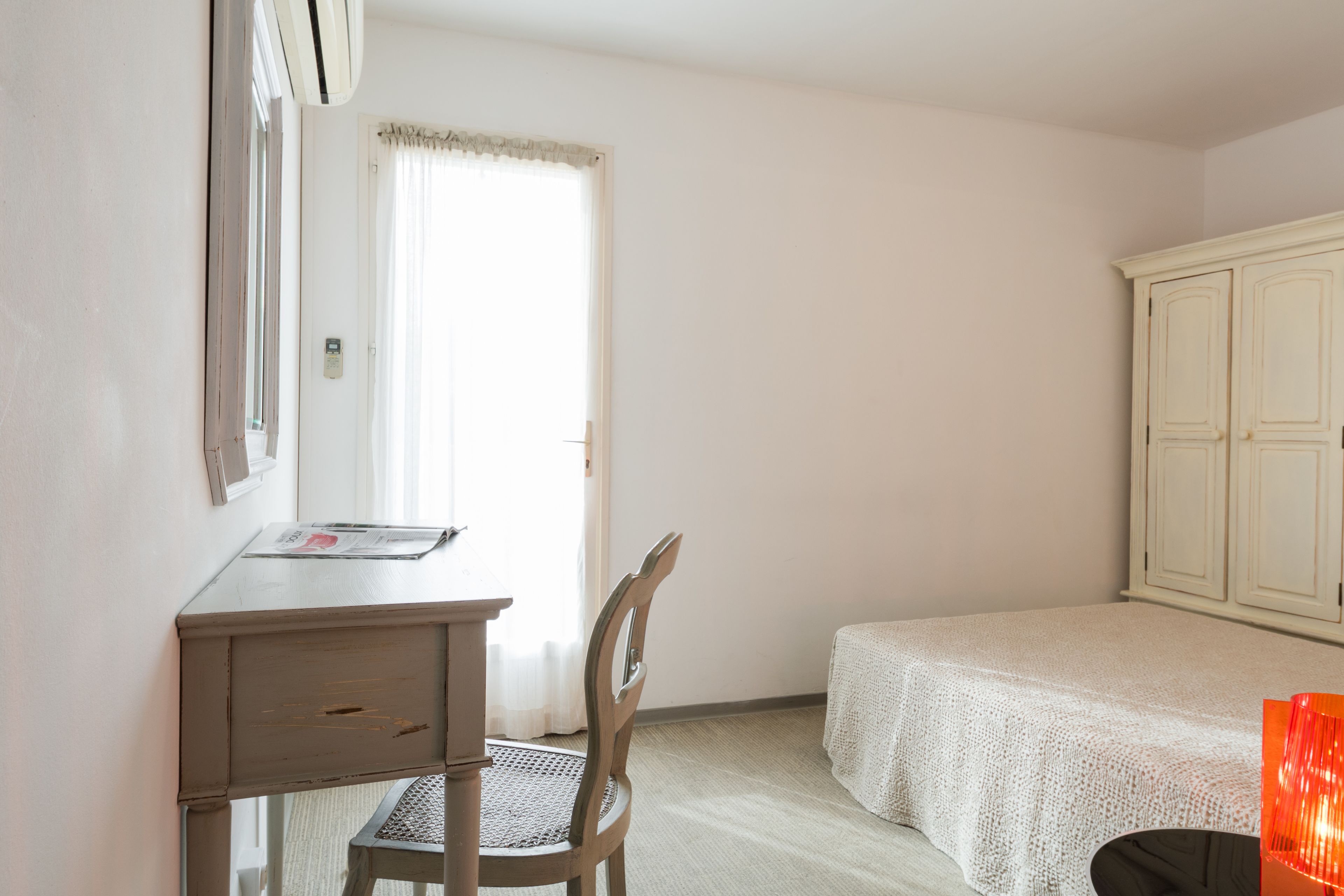 A room with a bed, a desk, a chair, and a wardrobe.