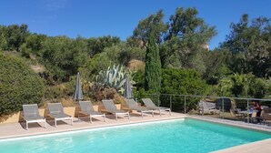 A swimming pool with lounge chairs and umbrellas, surrounded by lush greenery and trees. - Hôtel Cala di l'Oru (L'Île-Rousse)