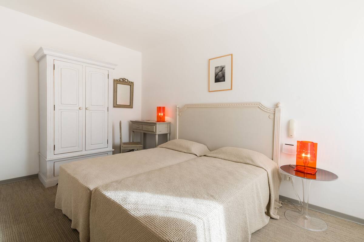 Un dormitorio con una cama, un armario, una mesita de noche y una lámpara.