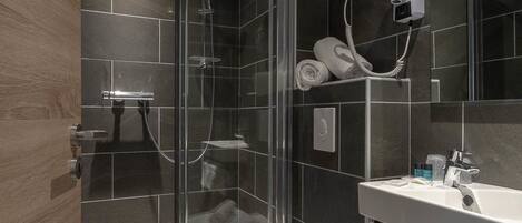 Un baño moderno con cabina de ducha de vidrio, inodoro, lavabo con espejo y toallas.