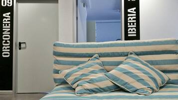 A bed with striped bedding and pillows, a closed door labeled "ORCONERA 09", and another door labeled "IBERIA 10".