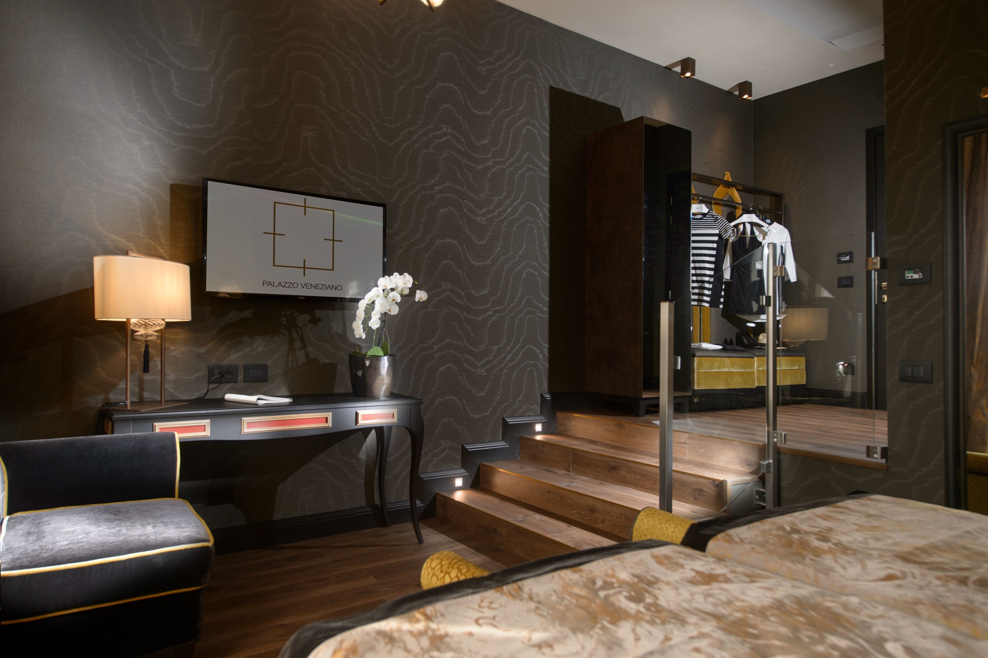 Una habitación de hotel moderna con una cama, un escritorio, una silla, una lámpara y una escalera que da a un ascensor.