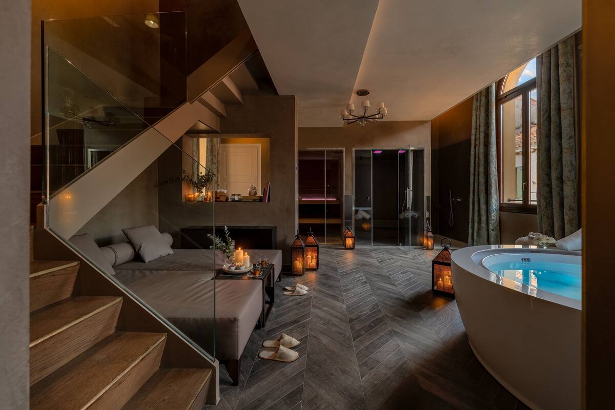 Ein modernes Interieur mit einer gebogenen Badewanne, einer Holztreppe und einer Sitzecke mit Kamin.