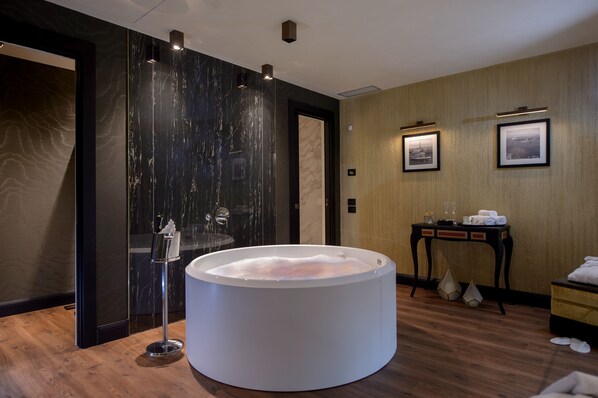 A modern bathroom with a large white bathtub, a wooden vanity, and a mirror. - Palazzo Veneziano (Venice)
